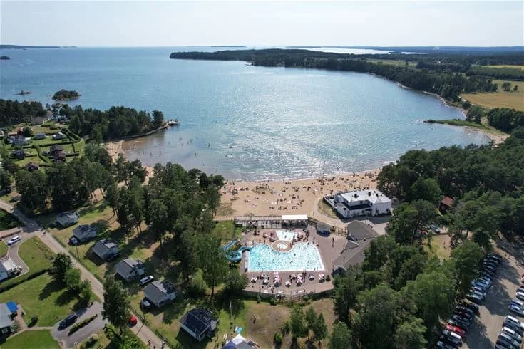 Flygfoto över Harge Bad & Camping med klarblå pooler, omgivna av grönt landskap och kustlinje. Perfekt destination för avkoppling och rekreation vid vattnet.