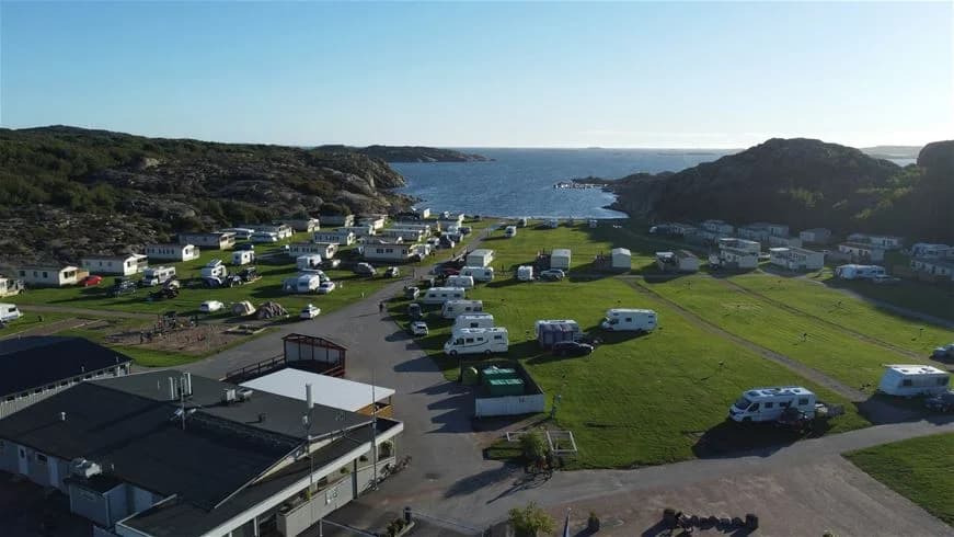 En buss parkerad vid Siviks camping med grönskande omgivning i bakgrunden.