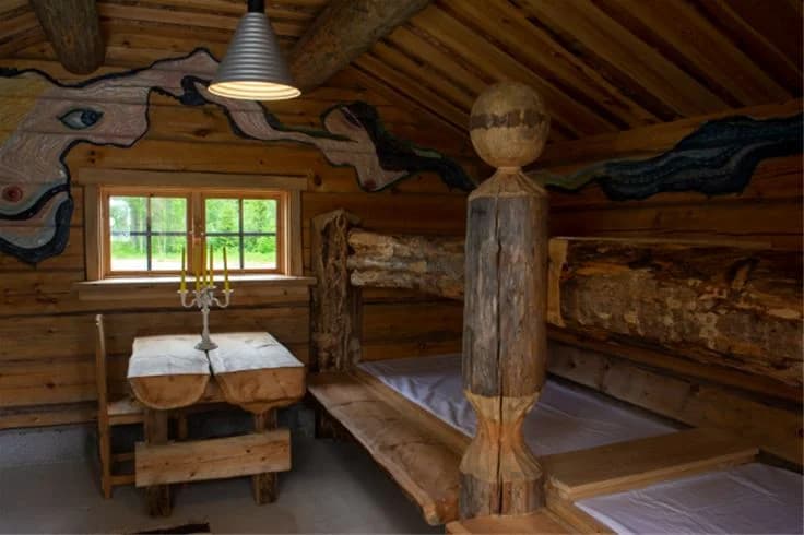 Alt-text: Interiör av en timmerstuga på koja byns camping med träbjälkar och plankor i taket, vilket ger en rustik och naturlig känsla.