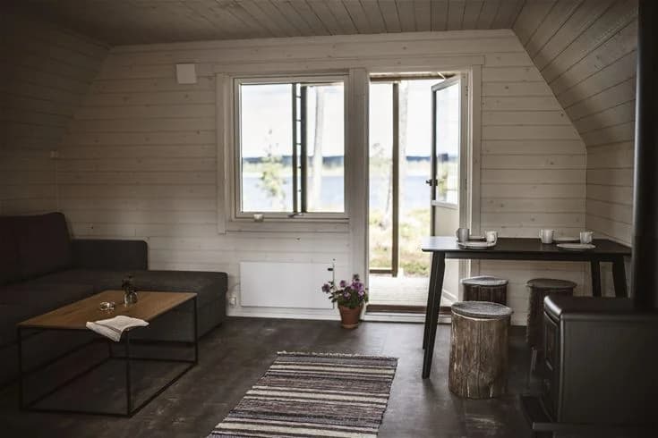 En mysig trästuga med ett golv av träplank i naturliga nyanser på Kojbyns camping.