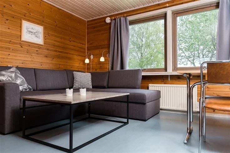 Ett möblerat vardagsrum på Mösseberg Camping med trägolv och träinredning, inklusive en soffa, soffbord och en matta.