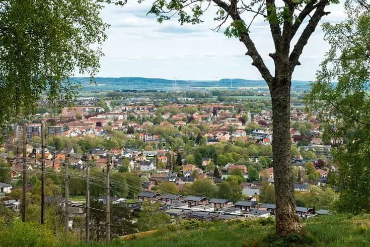Flygbild över Mösseberg camping, en bostadsområde omgiven av grönskande landskap, som visar närliggande bymiljö och urbana strukturer under våren.