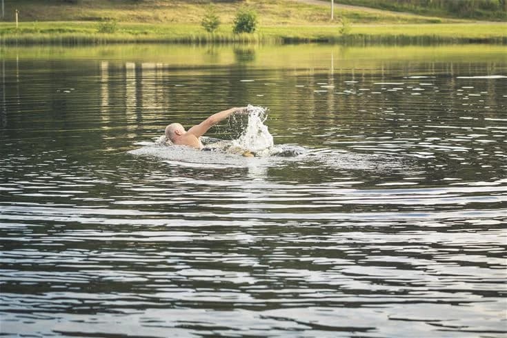 En sjö vid Mösseberg camping där människor njuter av friluftsliv. Det finns vattenaktiviteter och speglingar i vattnet.