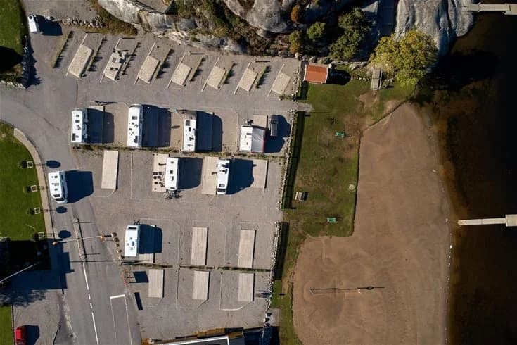 Flygbild av Lagunen Camping & Stugor med parkeringsplats där flera husbilar och lastbilar är parkerade längs en uppfart.