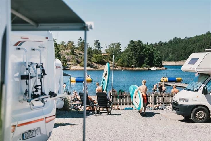 En husvagn och campingbil är parkerade vid Lagunen Camping & Stugor, omgivna av grönska och en lugn campingmiljö.