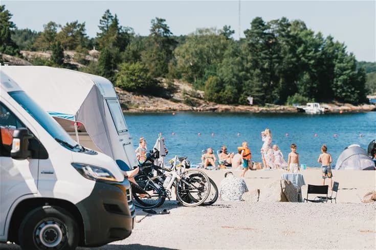 En husbil parkerad vid Lagunen Camping & Stugor, omgiven av skog och natur.