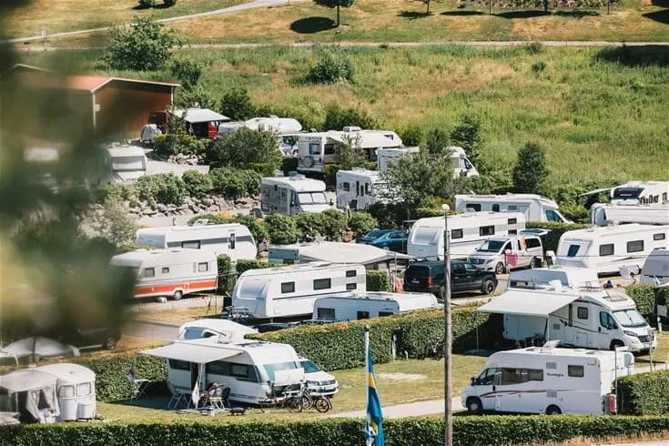 Luftfoto över Lagunen Camping & Stugor, med husbilar uppställda i parkeringsområdet omgivna av grönska.