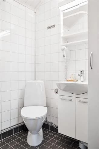 En ljus och ren badrumsmiljö på Lagunen Camping & Stugor, med en vit toalettstol som står på ett kaklat golv.