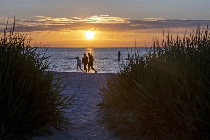 En strand i solnedgången med en horisont som glöder i orange och rosa nyanser, havet stilla mot kusten vid gröndals camping & stugor.
