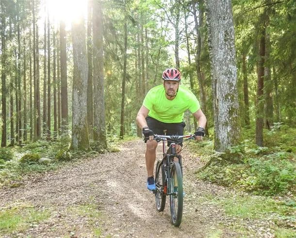 En grupp cyklister iklädda cykelutrustning står redo med sina cyklar på Ursand Resort & Camping, omgivna av natur i en aktiv och friluftsbetonad miljö.