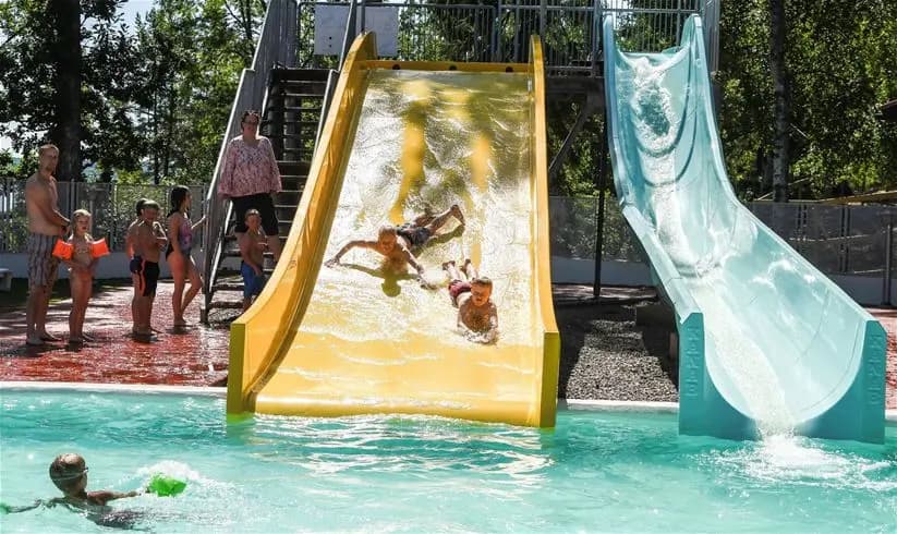 En somrig aktivitetsplats på Ursand Resort & Camping med vattenrutschkanor och lekutrustning utomhus, där familjer kan njuta av en dag med avkoppling och nöje i solen.