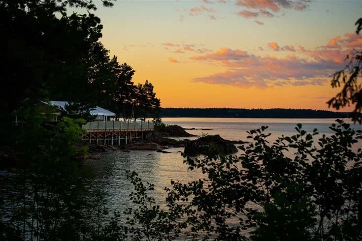 En vacker vy över en stilla vattensamling vid skymning, med horisonten i bakgrunden. Kusten och vattenvägar kring Ursand Resort & Camping skapar en fridfull naturmiljö.