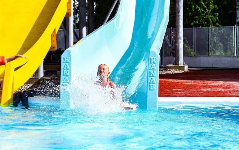 Sommaridyll på Ursand Resort & Camping med glada besökare som njuter vid poolområdet, utrustat med vattenrutschbanor och lekplatser, perfekt för en avkopplande semester.