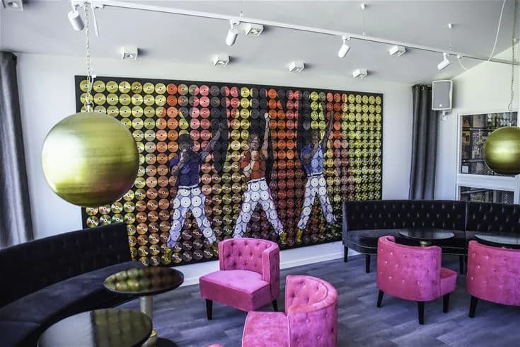 Ett välmöblerat rum på Ursand Resort & Camping med modern inredning. Det finns smakfullt placerade möbler, inklusive en dagbädd och flera stolar. Rummet har stilfull belysning från taklampor och ett ljust golv som skapar en inbjudande atmosfär.