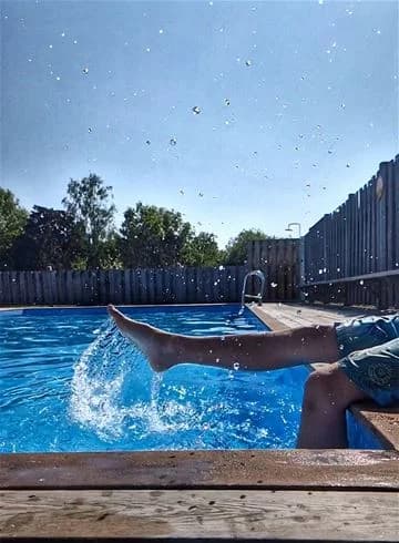 En blå swimmingpool på Stråvalla camping med besökare som simmar och njuter av kvällen.