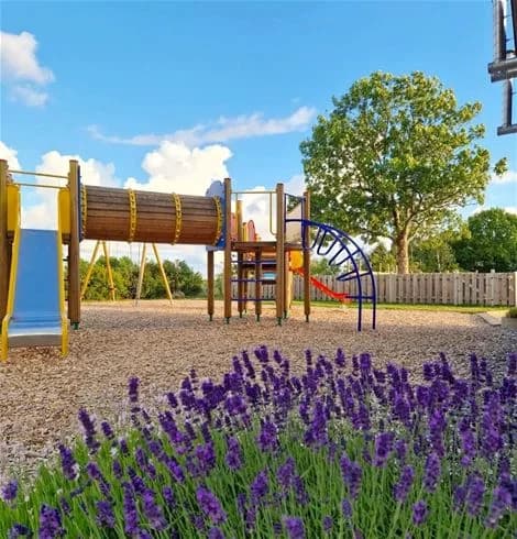 En lummig trädgård i vårskrud med lavendel och kattmynta vid Stråvalla Camping. En staket avgränsar området som är inrett med landskapsarkitektur.