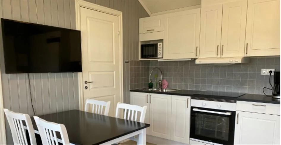 En inbjudande inredning på Skantzö Bad & Camping med trägolv och moderna möbler. Rummet har ett kök med vitvaror och skåp i trä.