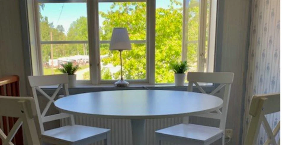 En bild av ett interiört utrymme på Skantzö Bad & Camping, med träinredning som inkluderar ett matbord och stolar på ett trägolv. Rummet har en hemtrevlig och naturlig atmosfär.