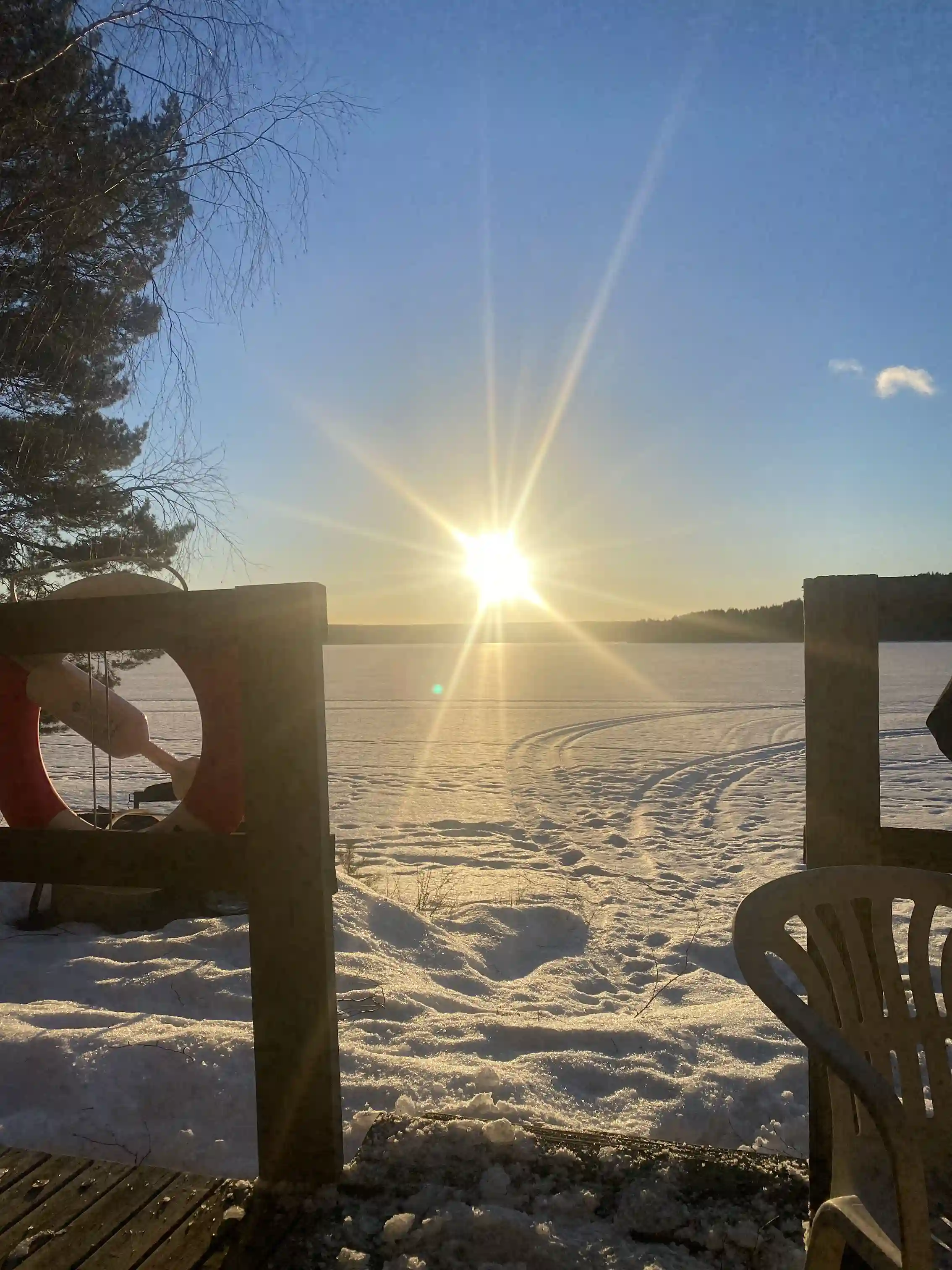 En vintermorgon vid Ore Fritidsby och Camping med snöbeklädd mark. Solen stiger upp vid horisonten, sprider gyllene ljus över det frostiga landskapet.