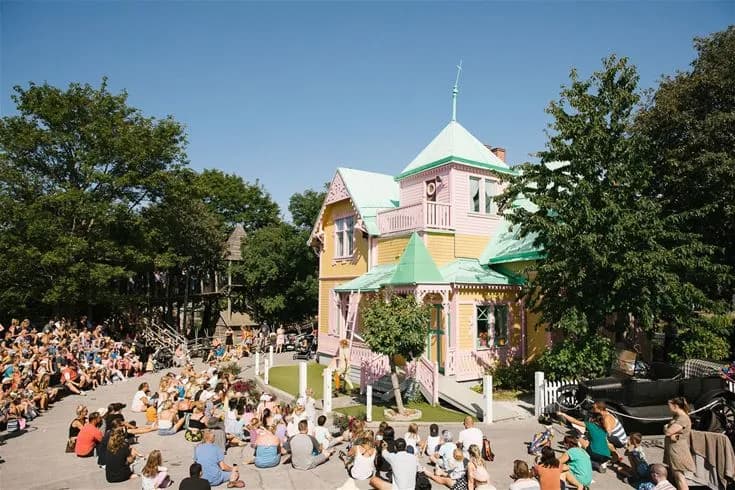 En grupp människor promenerar i en solig och grönskande miljö på Kneippbyn Resort Visby, en populär semesterort med fokus på rekreation och avkoppling.