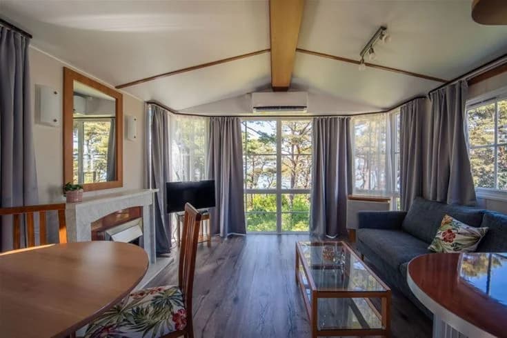 En träbyggnad vid Kneippbyn Resort Visby, delvis skuggad och omgiven av välskött grönska.