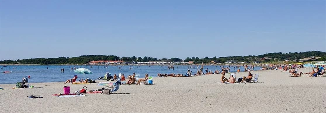 En solig dag på Apelvikstrand med människor som njuter av stranden vid havet. Perfekt plats för sommaraktiviteter och avkoppling vid kusten.