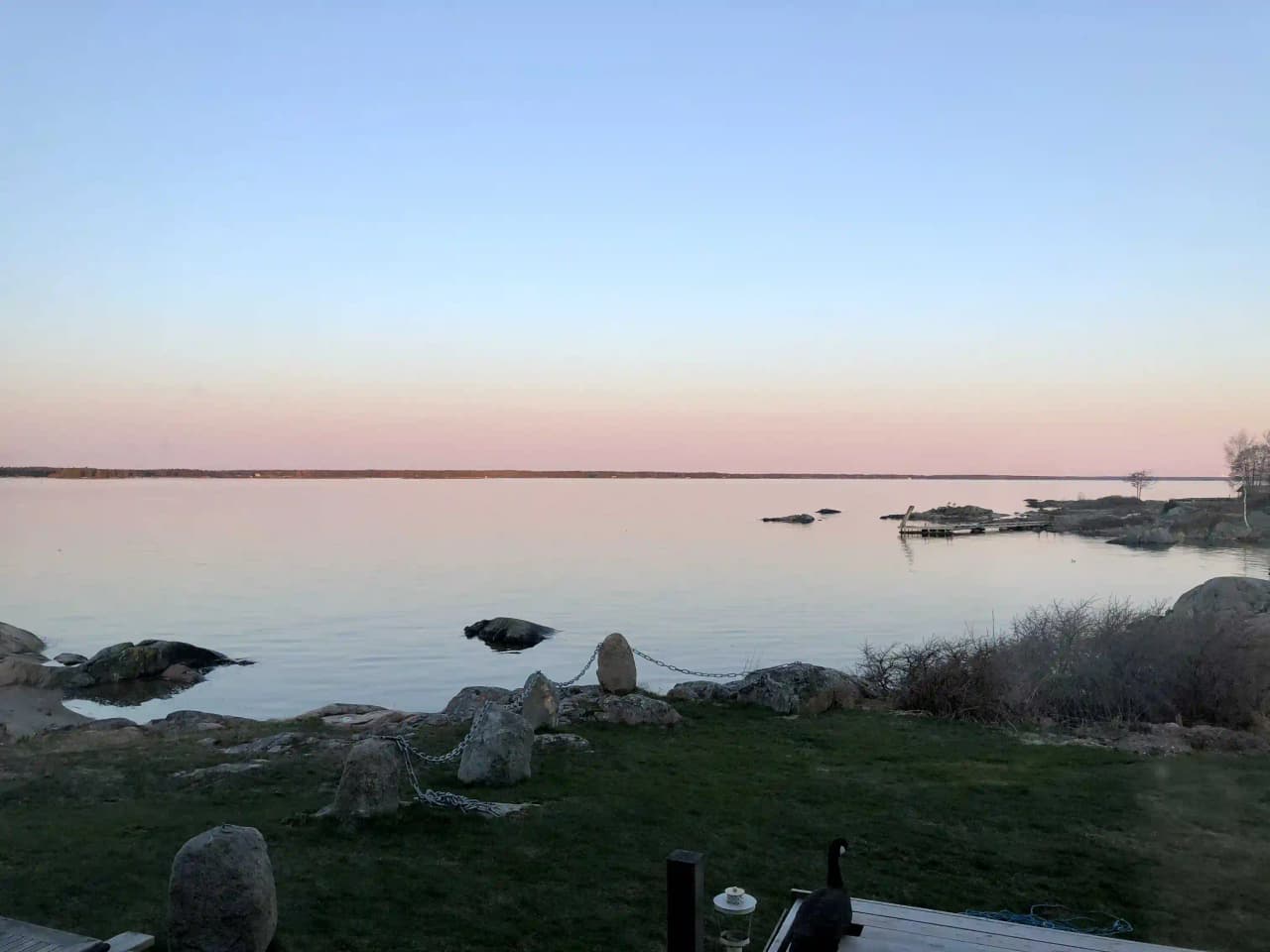 En sjö vid horisonten med klippor och strandkant i förgrunden, vid Gräsöbadens familjecamping.