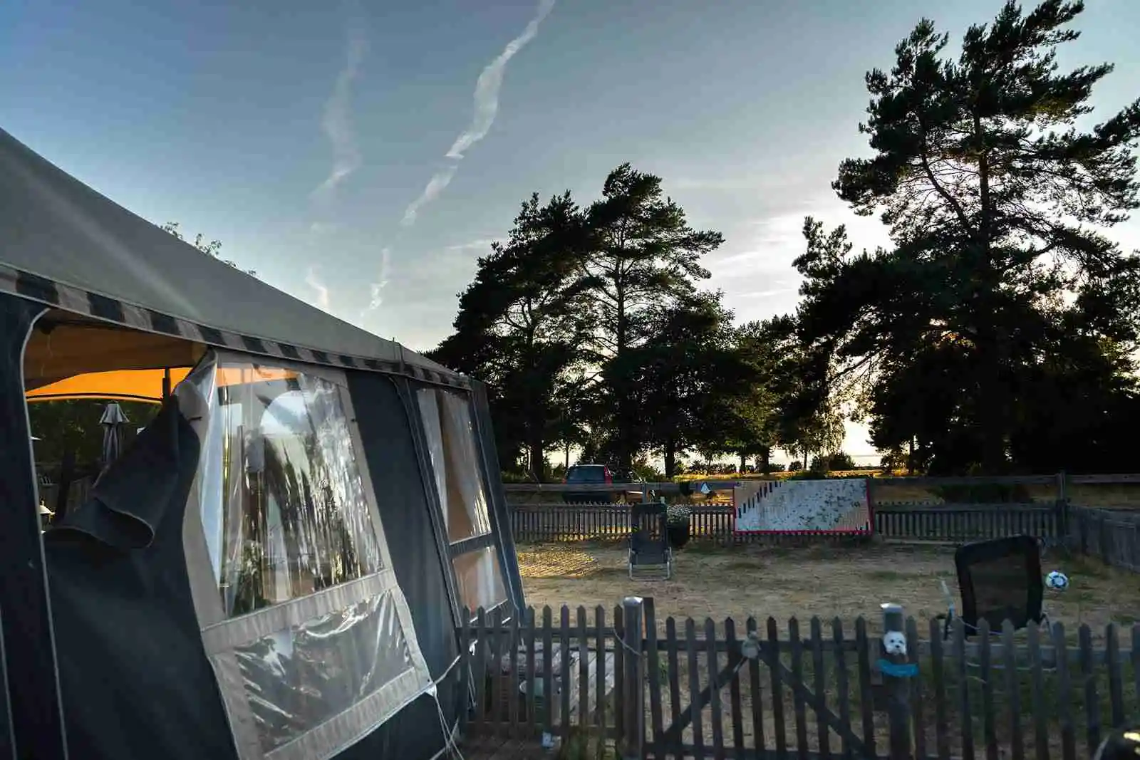 Bild av ett tält uppställt på en campingplats vid Haga Park Camping & Stugor. Ett sportfordon står parkerat nära tältet under en skuggande träd, med en presenning som ger extra skydd.