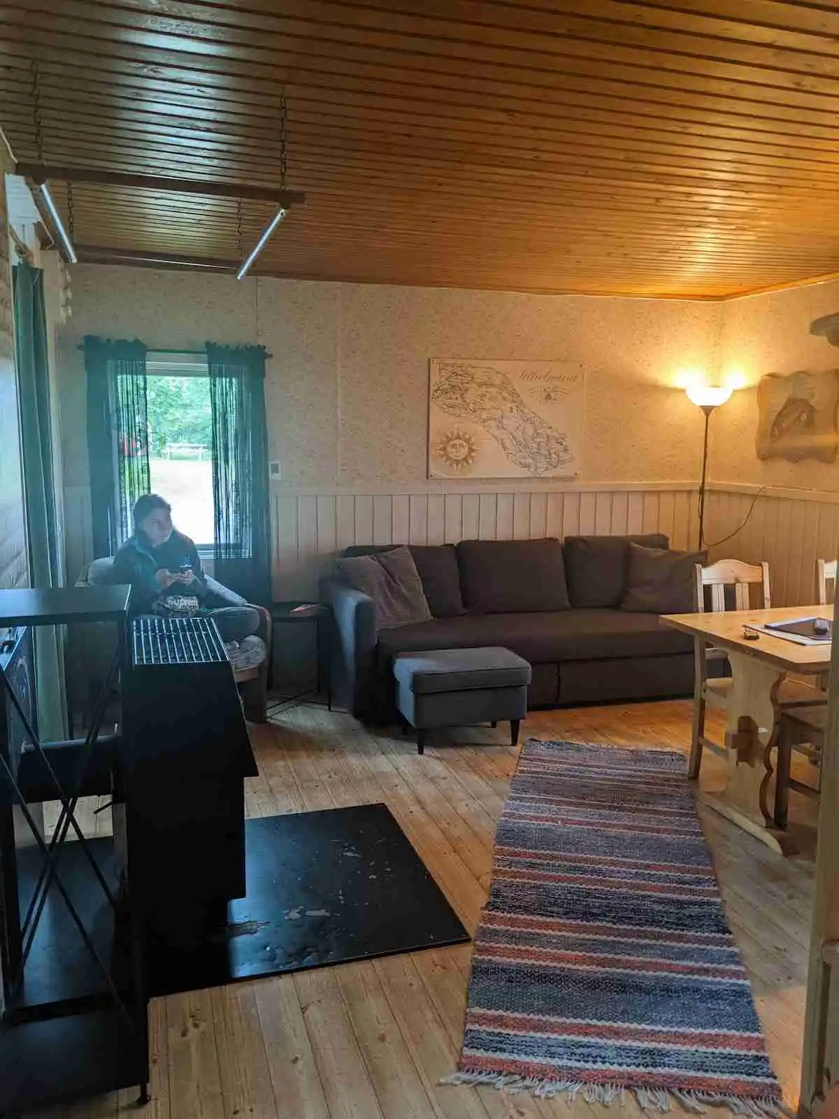 En mysig interiör av en stuga i Grönfjälls Fritidsby med trädetaljer, trägolv och bekväma möbler.