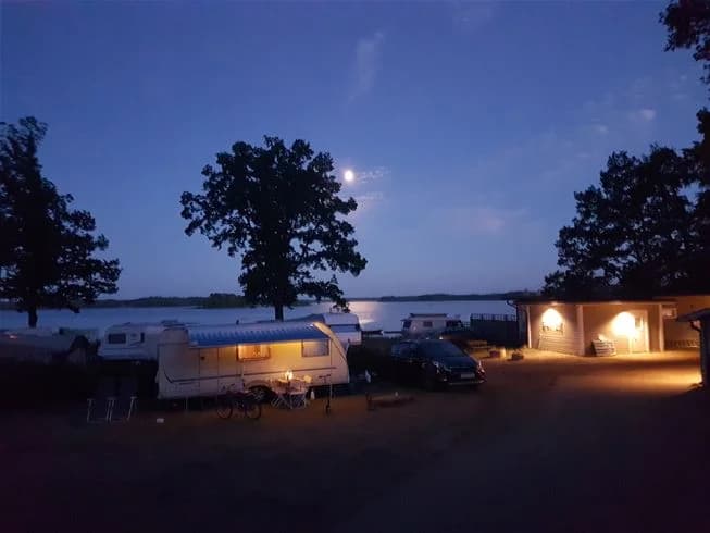 En husbil står parkerad vid kusten vid vallsnäs camping i skymningen, med utsikt över havet och stranden i kvällsljus.