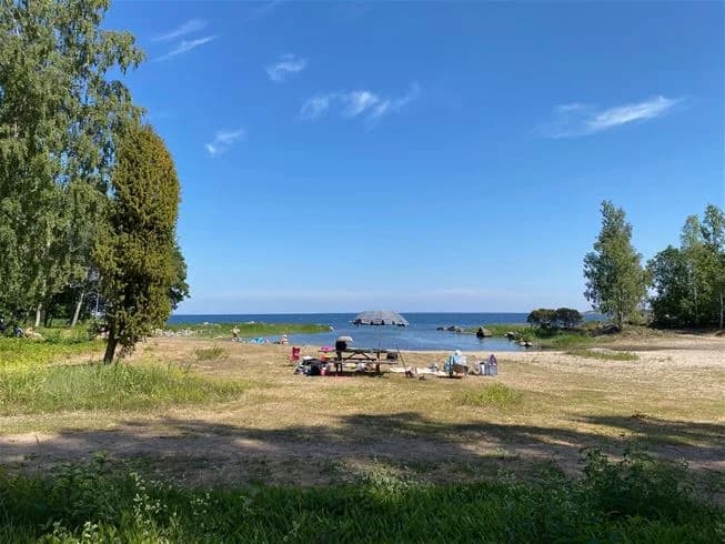En naturskön kuststräcka vid ängskärs havscamping med sandstrand, ängar och havsutsikt.