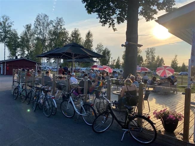 En cykel parkerad vid Hultsfred strandcamping, omgiven av cykelhjul och cykelramar, vilket antyder rekreation och fritidsaktiviteter på platsen.