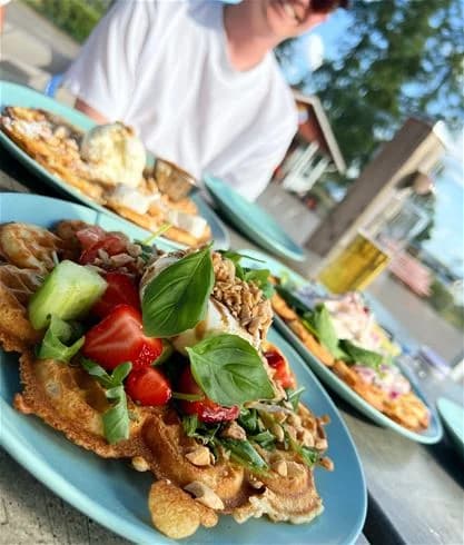 En tallrik med olika livsmedel, inklusive en sallad med grönsaker och frukt, på ett träbord.