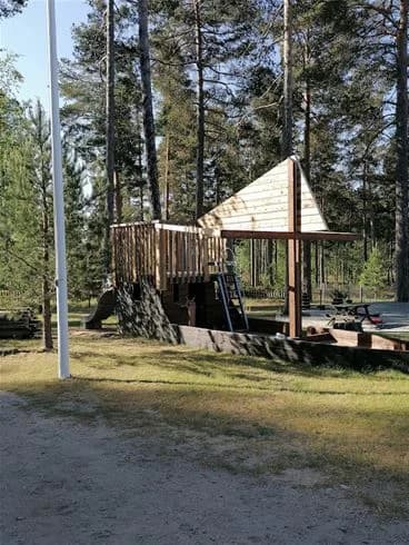 En skuggig träpaviljong omgiven av träd vid Norra Dellen Familjecamping.