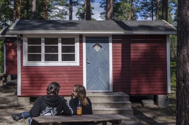 En trästuga på Norra Dellen Familjecamping omgiven av grönska och träd.