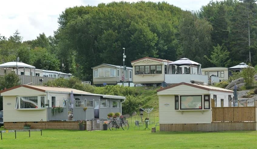 En skuggig campingplats med gröna ytor, parkerade husbilar och träd i närheten på Siviks Camping.