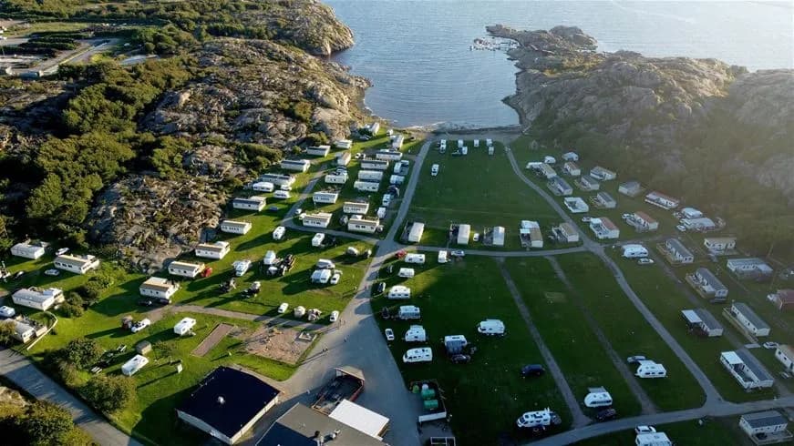 Flygfoto över Siviks Camping vid en vik, med campingområdet omgärdat av natursköna omgivningar och en glimt av vattnet.