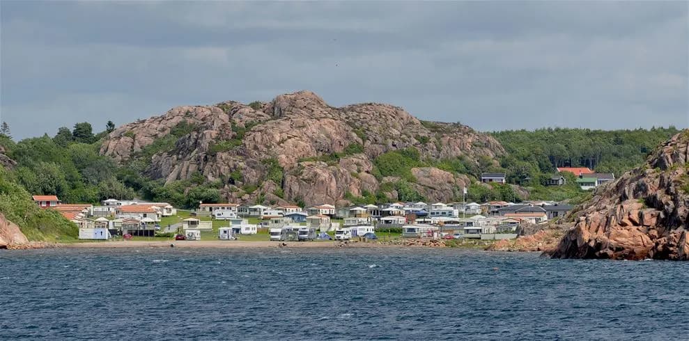 En klippig kust vid Siviks camping, med synliga bergformationer och utsikt över en vik och öar i bakgrunden.