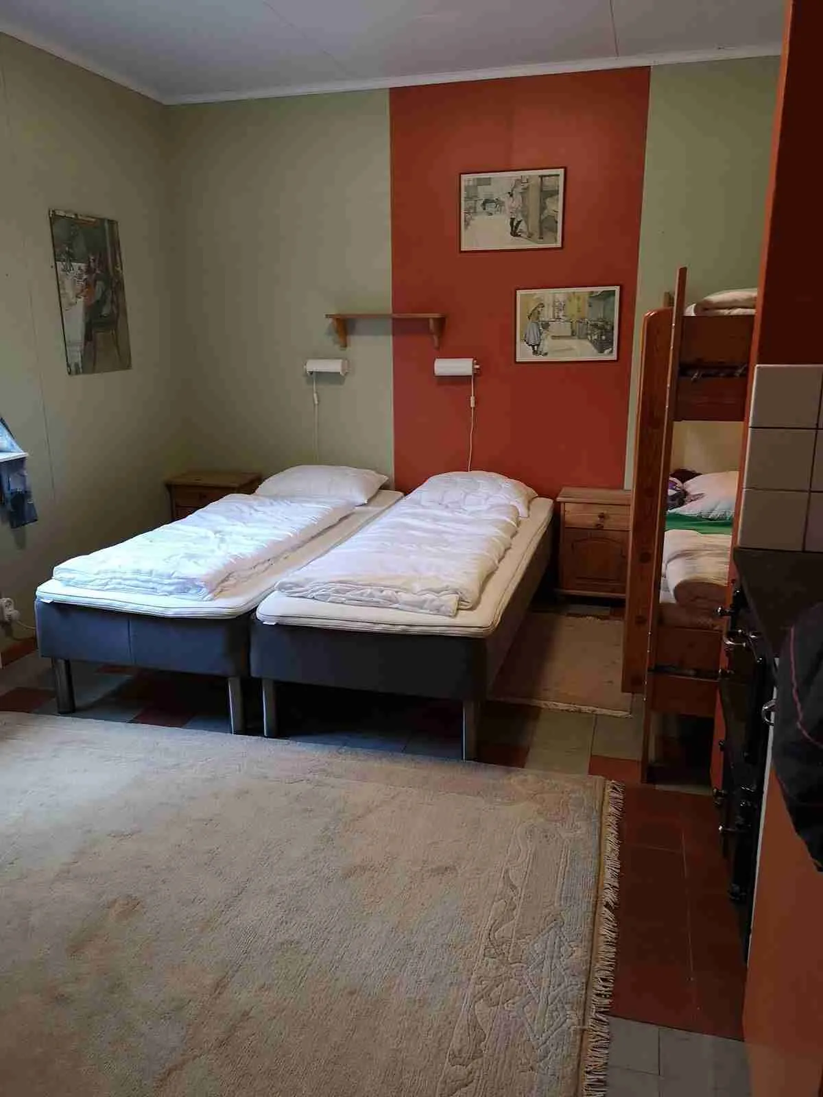 En ljus och inbjudande sovsal med flera enkelsängar utrustade med vita sängkläder. Rummet har ett trägolv och enkel inredning, vilket ger en hemtrevlig känsla.