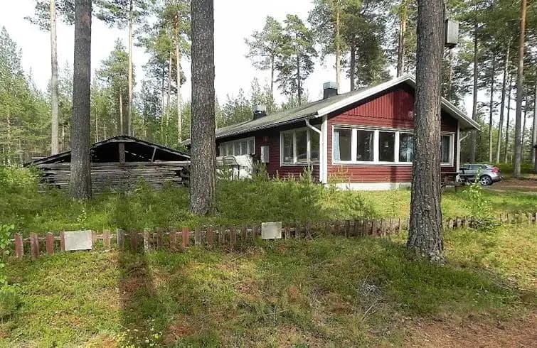 En mysig stuga omgiven av frodig grönska och höga träd på Norra Dellen Familjecamping, som ger en känsla av lantlig och avkopplande miljö mitt i naturen.