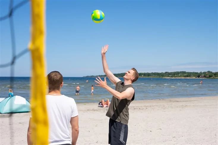 Bild på ett volleybollspel på Grönhag Camping. Några personer spelar volleyboll i sommarvädret, vilket skapar en inbjudande och rolig atmosfär för besökare.