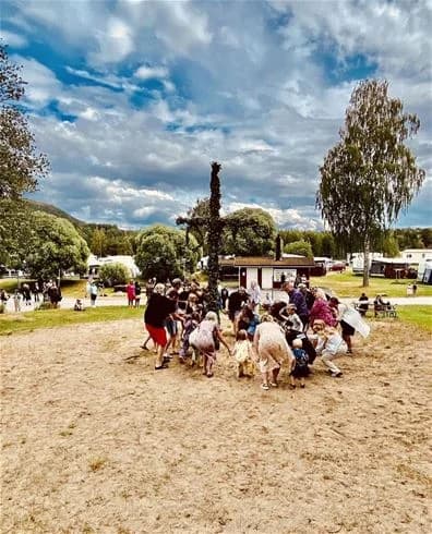 En livlig campingplats i Sollefteå där människor njuter av fritidsaktiviteter och promenader i en naturskön park.