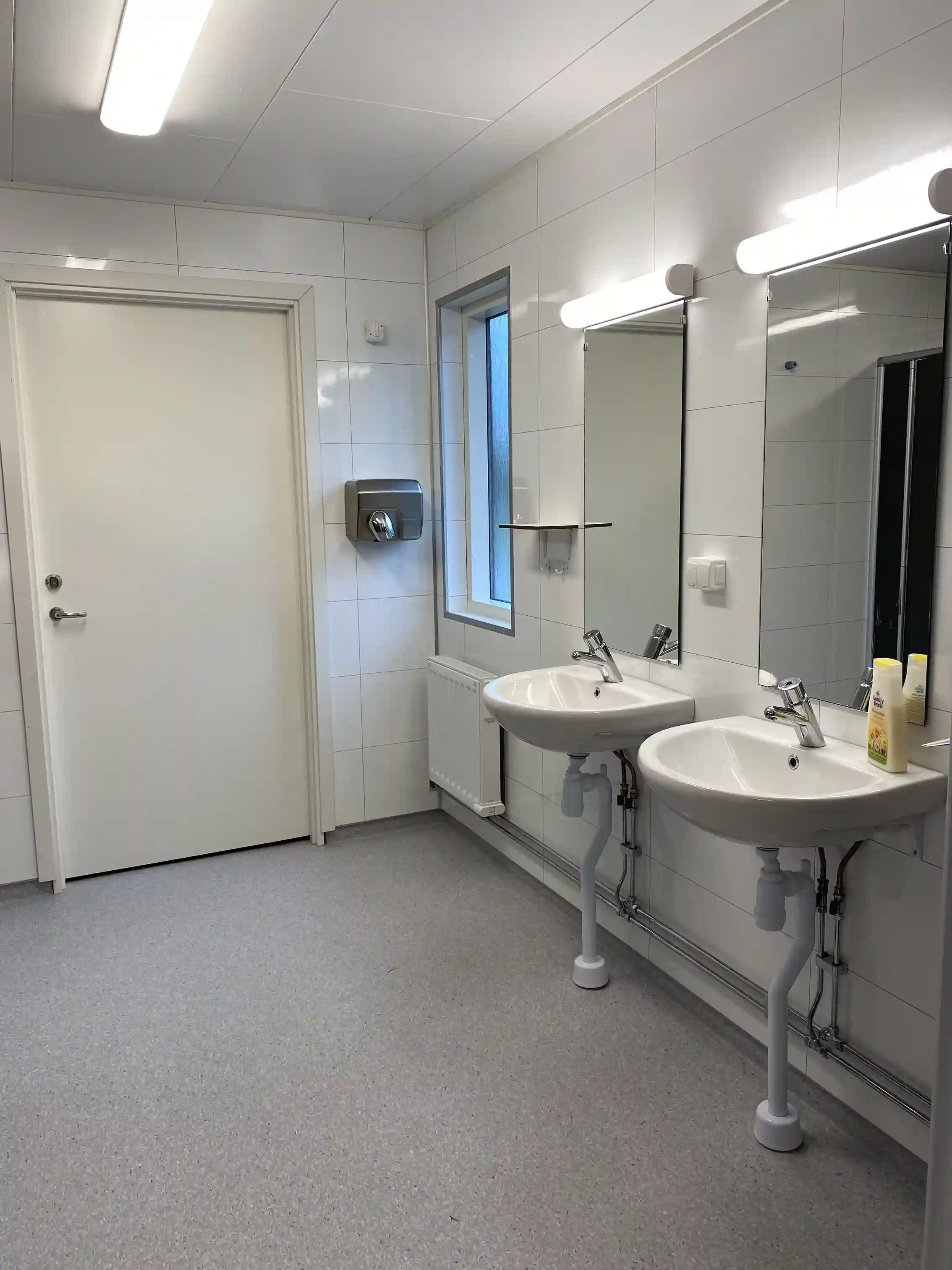 En modern och ren badrumsinredning med klinkergolv, handfat och vattenkran på Hjortsjöns camping.