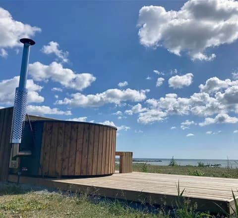 En träplattform med utomhusbord och stolar omgiven av grönska i Wikegårds semesterby & ställplatscamping.