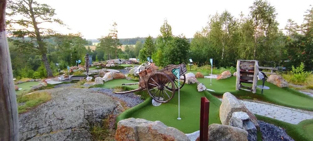 En minigolfbana omgiven av grönska i en parkmiljö, del av Lufta camping & restaurang. Perfekt för utomhusaktiviteter och avkoppling.