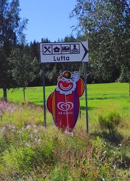 Bilden visar en skylt med logotyper och reklam för Lufta Camping & Restaurang.