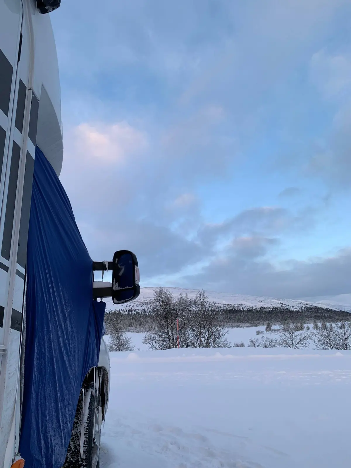 En vinterlandskap med snö och is, som skapar en frusen och arktisk atmosfär vid sjöstugan, omgiven av glaciärliknande formationer och tundra.