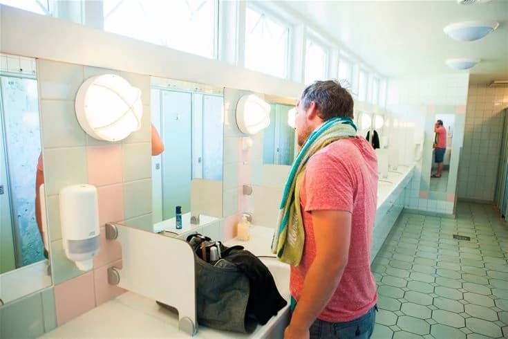 Ett modernt badrum med ett handfat, kran och spegel, del av Lisebergs camping Askim Strands faciliteter.