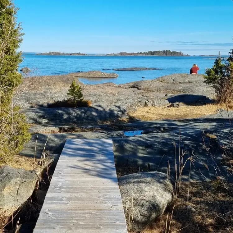 Vy över havet vid Ängskärs havscamping, med klarblå himmel och glittrande vatten längs den steniga kusten.
