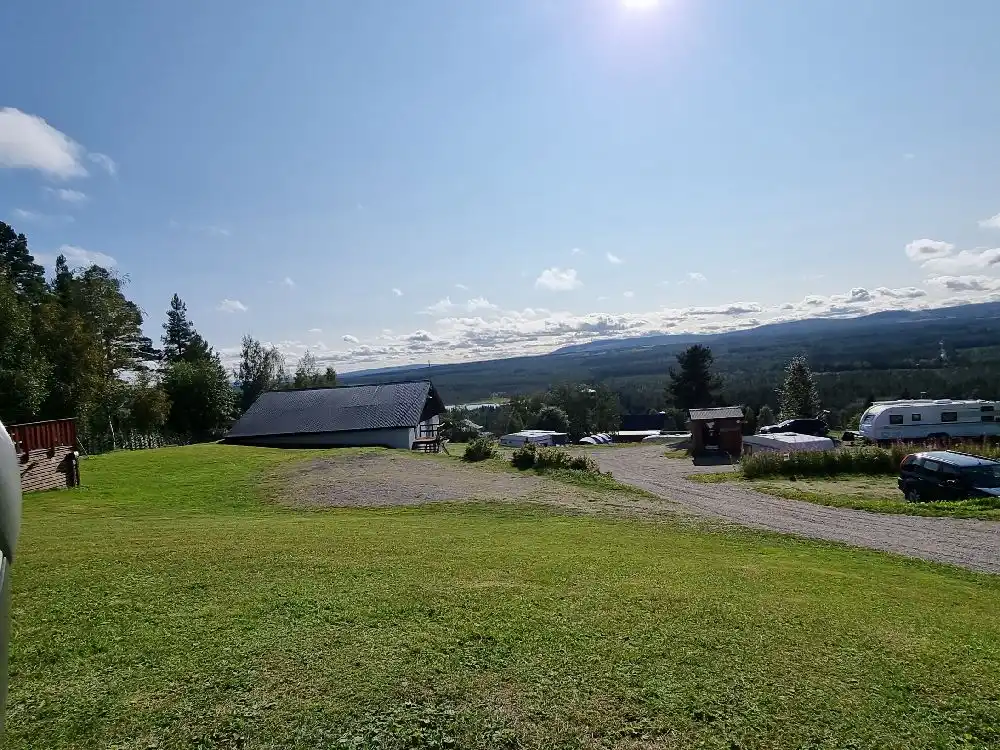 En gräsbevuxen slätt under en molnig himmel, med tält uppsatta för camping i det natursköna området Kvarnsjö Camp.